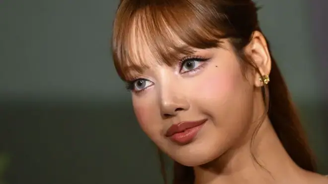 Lisa站在紅地毯上，目光望向鏡頭外；閃光燈的光線照亮了她的雙眼。