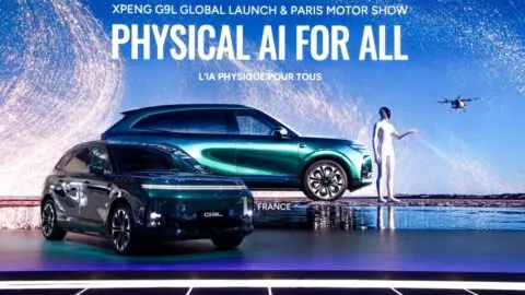 Xpeng G9L SUV displayed onstage beneath a screen reading "Physical AI for all" at its Paris launch.
