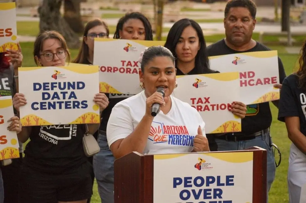 Stephanie Maldonado, the political director of LUCHA, speaks at a rally to stop data centres. She is surrounded by protestors holding signs that say "defund data centres"