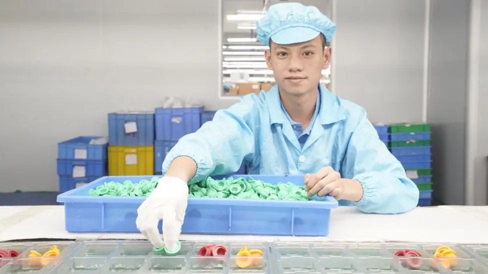 A worker at the Mihox factory in Dongguan sorting out moulded plastic parts. He is wearing blue overalls and a blue hat