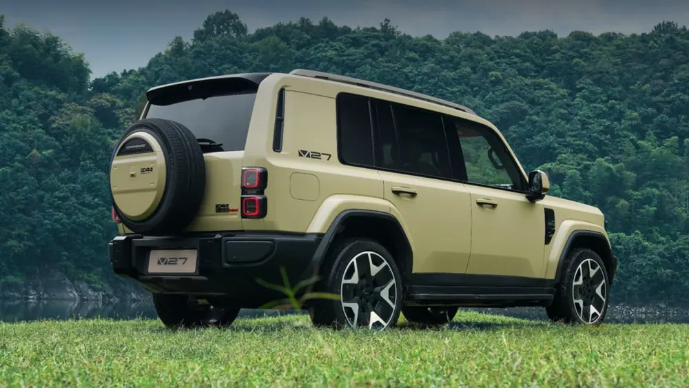 Beige iCar V27 viewed from the rear beside a lake, showing its tailgate-mounted spare tire.