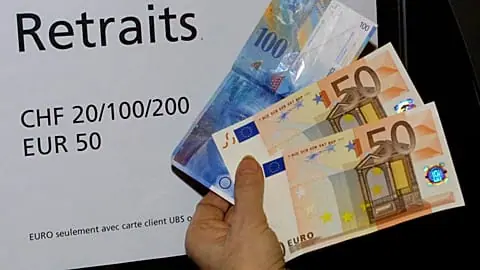 A woman holds 100 euro (pink banknotes at bottom) and 100 Swiss francs (blue banknote at top) she withdrew from an ATM in a bank in Geneva, Switzerland, on Tuesday, Jan. 8, 20