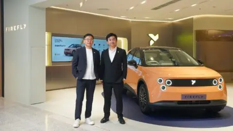 Firefly president Daniel Jin, left, poses with another man beside an orange Firefly EV at the Bangkok store.