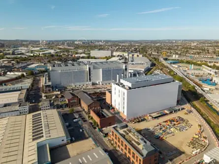 An aerial view of large grey and white datacentre buildings and a construction site in