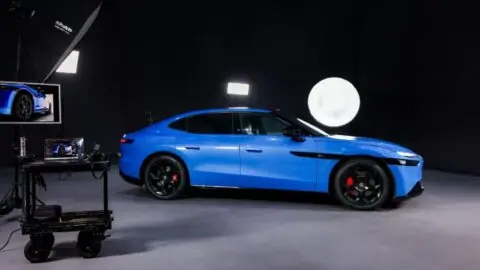 Side view of a blue Volkswagen ID. UNYX 09 surrounded by studio lighting and camera equipment.