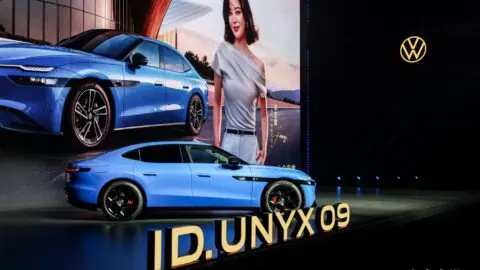 Blue Volkswagen ID. UNYX 09 displayed onstage behind large lettering bearing its model name.
