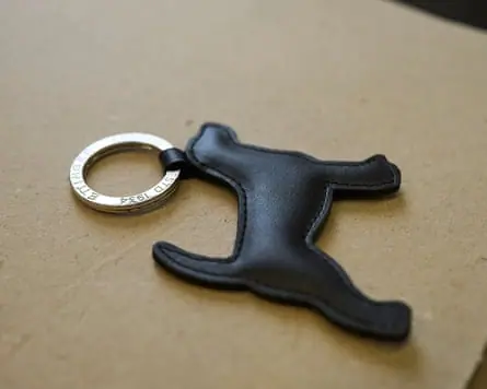 A black leather dog-shaped keyring charm from Ettinger lies beside a silver keyring