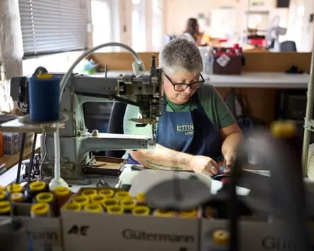 A worker sews leather at an industrial sewing machine