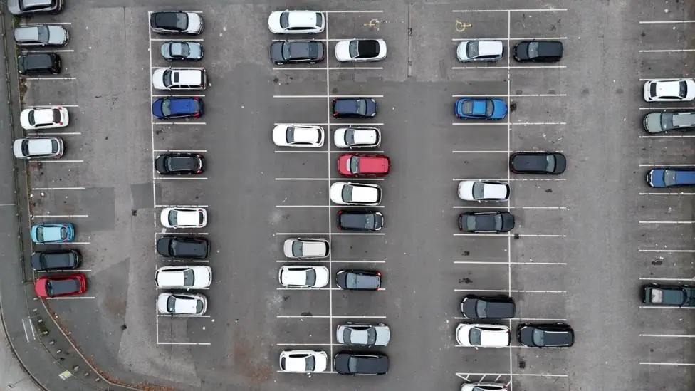 An aerial view of a car park with lots of cars in different colours