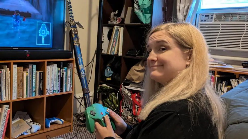Sitting on the floor in front of her TV, Kacey Doran holds a console controller